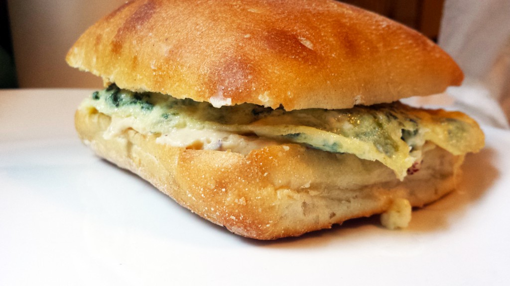 Hummus and scrambled egg with spinach pie filling on ciabatta
