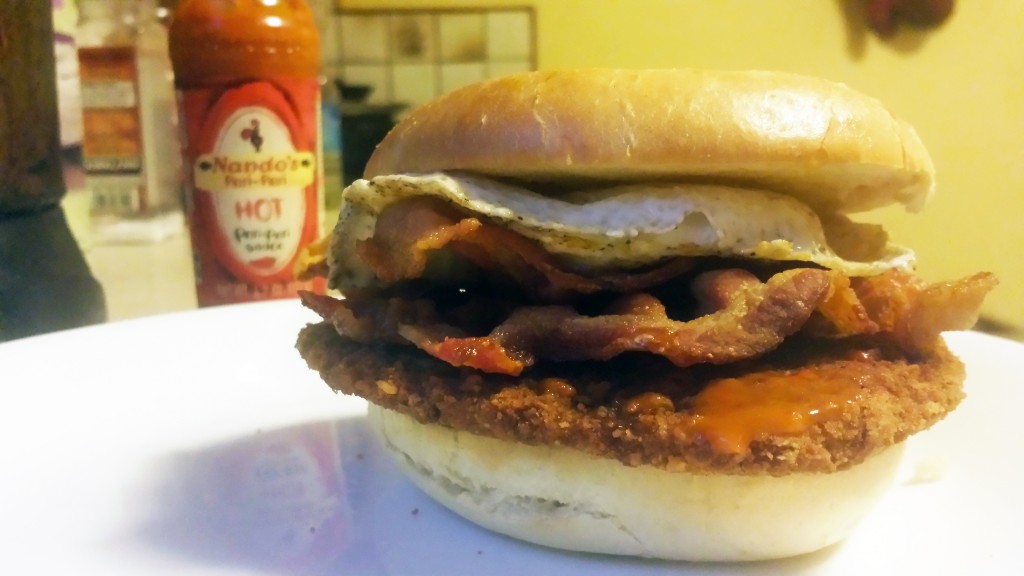 pork fritter with bacon, egg, hot sauce on bagel