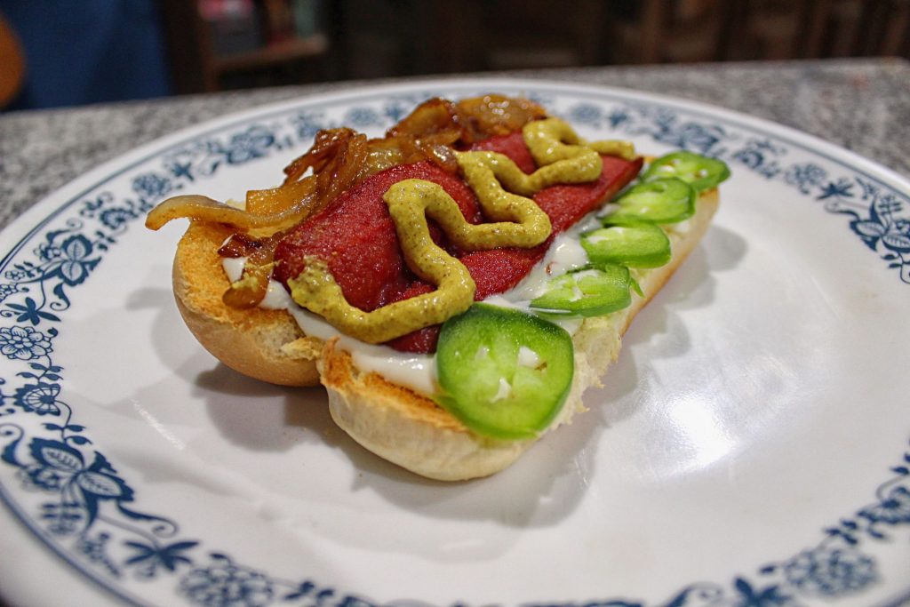 Seattle style hot dog with cream cheese, grilled onions, sliced jalapenos, and spicy brown mustard