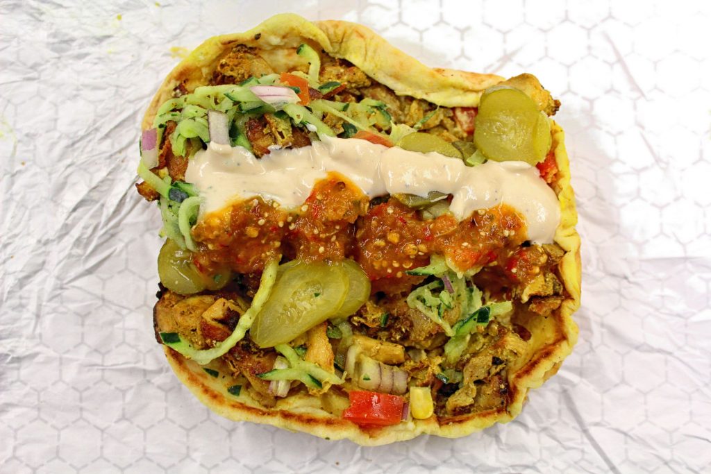 Chicken shawarma from Benjyehuda with hummus, cucumber salad, onion, tomato, pickle, tahini, and hot sauce